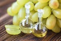 Healing grapes seeds oil in a glass jar, fresh grapes on old wooden background, seed extract has antioxidant and nourishing the sk