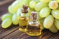 Healing grapes seeds oil in a glass jar, fresh grapes on old wooden background, seed extract has antioxidant and nourishing the sk