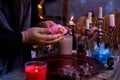 Healing session in the salon of healer, herbalist, close-up of hands of female psychic hold rose quartz stone, burning candles,