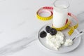 Health breakfast.Concept of diet and lose weight.Kefir,spoon with cottage cheese on circle plate,prunes and yellow measure tape