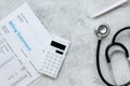 health care billing statement with doctor's stethoscope and pen on stone background top view Royalty Free Stock Photo