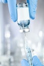 Health care concept with a hand in blue medical gloves holding a vaccine vial with blue liquid and black white label Royalty Free Stock Photo