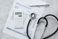 Health care costs with billing statement, stethoscope and calculator on stone table top view Royalty Free Stock Photo