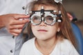 Health care of the eyes. Doctor checking little girl sight and tuning the phoropter