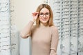 Health care, eyesight and vision concept - happy woman choosing glasses at optics store. Portrait of beautiful young Royalty Free Stock Photo