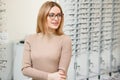 Health care, eyesight and vision concept - happy woman choosing glasses at optics store. Portrait of beautiful young Royalty Free Stock Photo