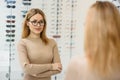 Health care, eyesight and vision concept - happy woman choosing glasses at optics store. Portrait of beautiful young Royalty Free Stock Photo