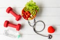 Health Care. Fresh vegetable salad with medical stethoscope and equipment dumbbell for diet and weight loss