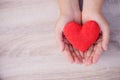 hands holding handmade red heart on wooden background. Royalty Free Stock Photo