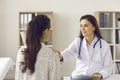 Doctor talking to young woman and touching her shoulder to reassure, support and cheer up