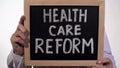 Health care reform text on blackboard in doctor hands, state government policy