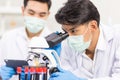 Health care researchers working in biological science laboratories, a researcher uses a microscopic and his assistant using a Royalty Free Stock Photo