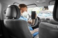 Male car driver in mask showing smartphone