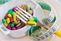 health care and wellness - diet pills and loosing weight - various tablets in a pot with measuring meter and forks