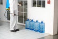 Health care worker in white jumpsuit and protective face mask using spraying machine to disinfect virus pandemic.  Health care and Royalty Free Stock Photo