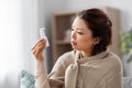 Sick asian woman with oral spray medicine at home