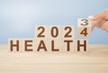 2024 health concept. Hand flip wooden cube change year 2023 to 2024. gray background, copy space. Hand flip wooden cube change on