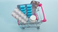 Health concept, pills in a trolley from a supermarket on a blue background, top view, complex treatment of medicines