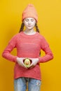 Human Health Concepts. Teenager Girl In Coral Knitted Clothing With Split Avocado Fruit In Front of Belly as a Demonstration of