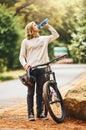 Health, cycling and woman drinking water on a break in nature to hydrate, wellness and resting outdoors. Sports
