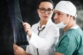 Health diagnostic in hospital. male surgeon in mask and female doctor or nurse with stethoscope reviewing x-ray scan Royalty Free Stock Photo