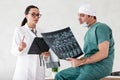 Health diagnostic in hospital. male surgeon in mask and female doctor or nurse with stethoscope reviewing x-ray scan Royalty Free Stock Photo