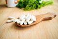 Health effects of coagulations vitamin. White capsules of vitamin K (phylloquinone) in wooden spoon on a background of a bottle o