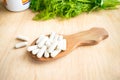 Health effects of coagulations vitamin. White capsules of vitamin K (phylloquinone) in wooden spoon on a background of a bottle o