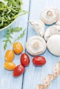 Health food. Fresh mushrooms and arugula salad, cherry tomatoes on light blue background. Diet meals. Royalty Free Stock Photo