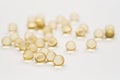 Health food supplement: Close up of Vitamin D3 softgels spilt across a white background. 1