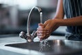 The health inspector would be very proud. a woman washing her hands in the sink of a commercial kitchen.