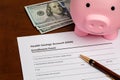 Health savings account, HSA, form with piggy bank and cash money. Royalty Free Stock Photo
