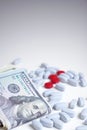 Health insurance, medical ethics concept. Red and blue pills on white background next to a wad of cash. Royalty Free Stock Photo