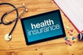 Health insurance title on tablet computer placed on doctors desk Royalty Free Stock Photo