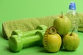 Dumbbells in green color, bottle, measure tape, towel and fruit Royalty Free Stock Photo