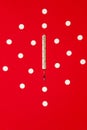 Health and medical background, vertical view. Thermometer and white pills on red background. Medical background.