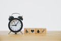 Health and medical icon on wooden block and black analog alarm clock on wood desk for health insurance, nonstop medical service