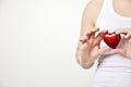 health, medicine and charity concept close up of female hands with small red heart holding for breast on white