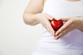 health, medicine and charity concept close up of female hands with small red heart holding for breast on white