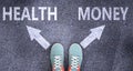 Health and money as different choices in life - pictured as words Health, money on a road to symbolize making decision and picking