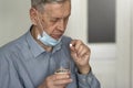 An elderly man in a medical mask takes a pill. Royalty Free Stock Photo