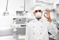 Chef in respirator showing ok sign at kitchen