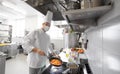 Chef in mask cooking food at restaurant kitchen Royalty Free Stock Photo