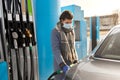 Woman in mask filling car at gas station Royalty Free Stock Photo