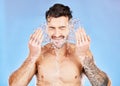 Health, skincare and water splash, man on studio background happy and topless with tattoo washing face. Smile, wellness