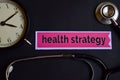 Health Strategy on the print paper with Healthcare Concept Inspiration. alarm clock, Black stethoscope.