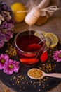 health, traditional medicine, folk remedy concept - dripping sweet honey on cup of tea.