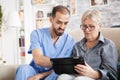 Health visitor helping senior woman to use tablet Royalty Free Stock Photo