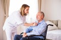 Nurse and senior man in wheelchair during home visit. Royalty Free Stock Photo