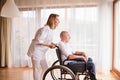 Nurse and senior man in wheelchair during home visit. Royalty Free Stock Photo